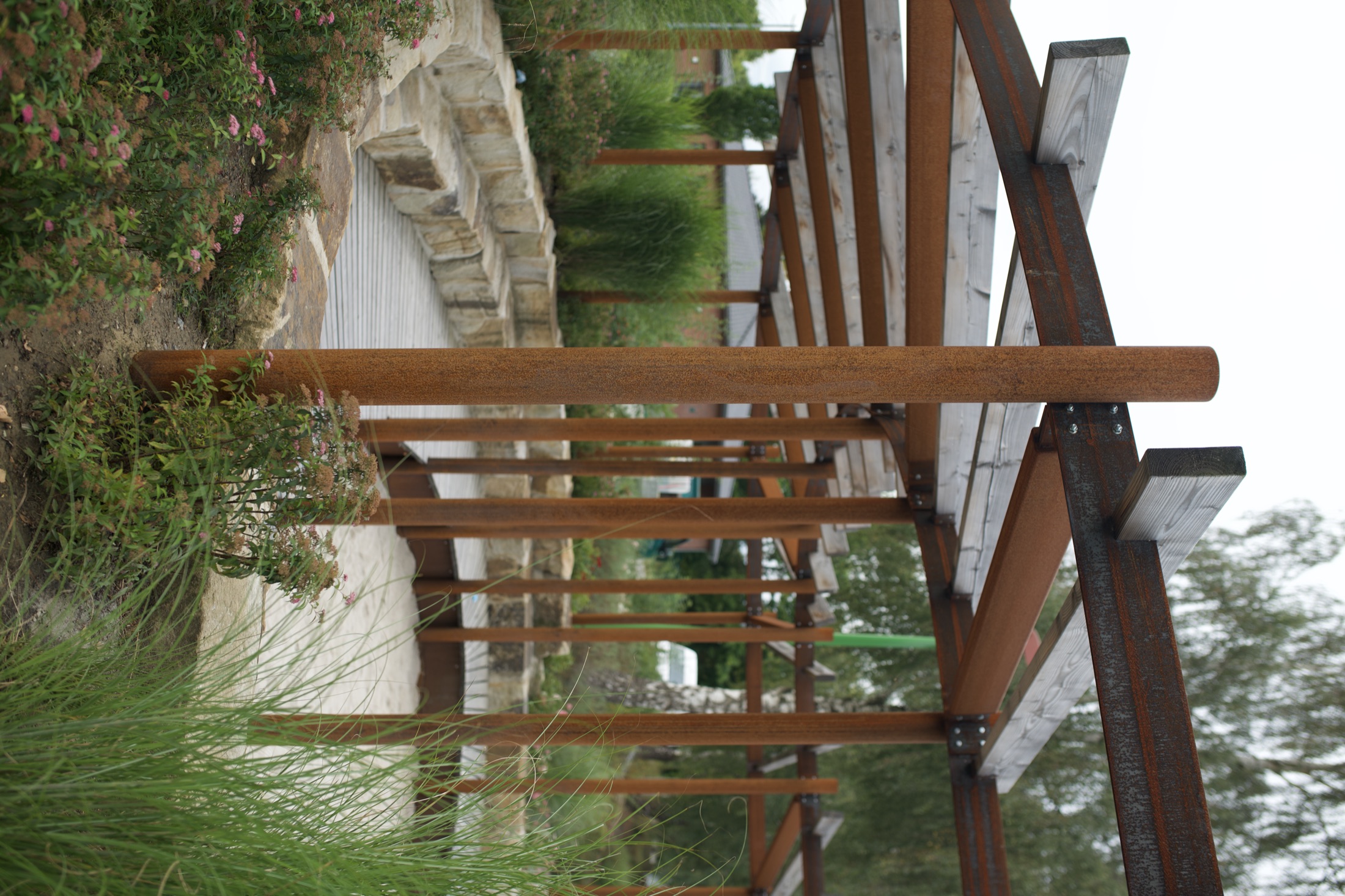 Von Richter gestaltete Außenanlage mit Pergola aus Holz und Cortenstahl, Natursteinpfad und Ziergräsern